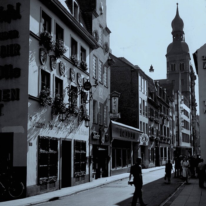 Auf dem Bild ist ein Laden im Zentrum von Bonn mit dem Schriftzug C.J. Adam zu sehen. Das schwarz-weiße Bild ist aus den 80er Jahren.